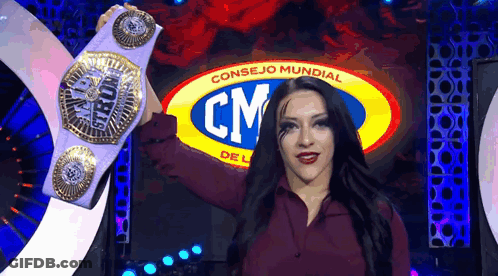 A Woman Is Holding A Championship Belt In Front Of A Cm Logo . GIF