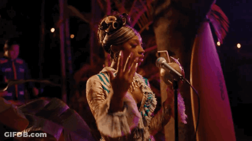 A Woman Is Holding A Coconut In Front Of A Microphone . GIF