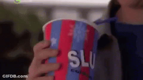 A Woman Is Holding A Colorful Cup Of Slushy Ice Cream . GIF