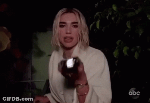 A Woman Is Holding A Flashlight In Her Hand And Looking At The Camera . GIF
