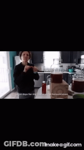 A Woman Is Holding A Glass In A Kitchen And Says This Is For The Flavor To Really Soak In .. GIF