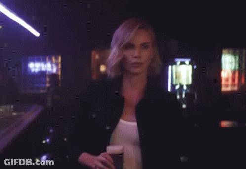 A Woman Is Holding A Glass Of Beer With The Words Hold My Beer Behind Her GIF