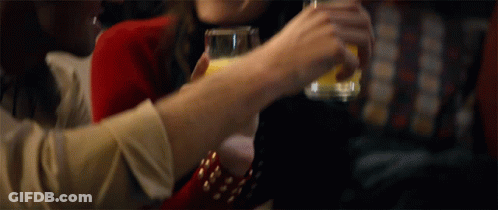 A Woman Is Holding A Glass Of Orange Juice In Her Hand GIF