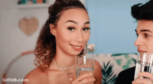 A Woman Is Holding A Glass Of Water Next To A Man Holding A Glass Of Water . GIF