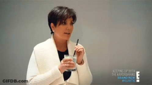 A Woman Is Holding A Glass Of Water With A Straw In Her Mouth . GIF