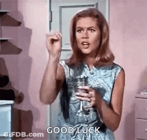 A Woman Is Holding A Glass Of Wine And Giving A Good Luck Sign . GIF