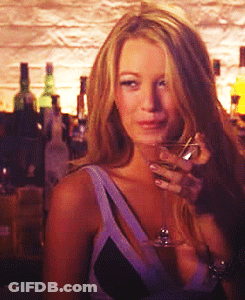 A Woman Is Holding A Glass Of Wine In Front Of A Bar GIF