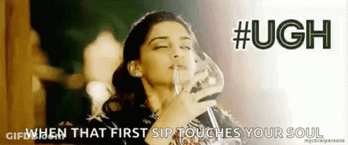 A Woman Is Holding A Glass Of Wine In Her Hand And Drinking From It . GIF