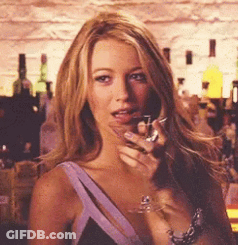 A Woman Is Holding A Glass Of Wine In Her Hand In A Bar . GIF