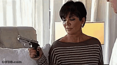 A Woman Is Holding A Gun In Her Hand In A Bedroom . GIF