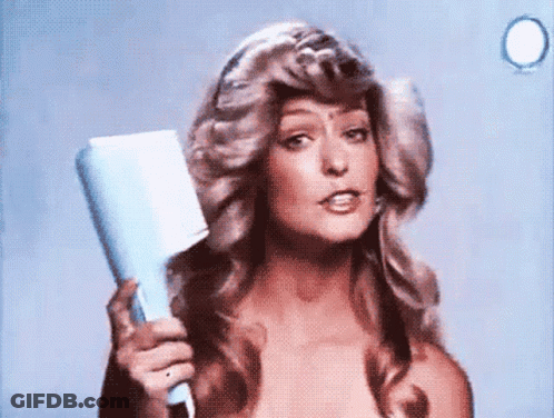 A Woman Is Holding A Hair Dryer In Her Hand And Looking At The Camera GIF