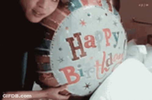 A Woman Is Holding A Happy Birthday Balloon In Her Hands . GIF