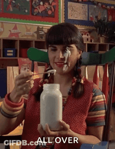 A Woman Is Holding A Jar Of Mayonnaise With A Spoon In Her Mouth And The Word All Over Is On The Bottom . GIF