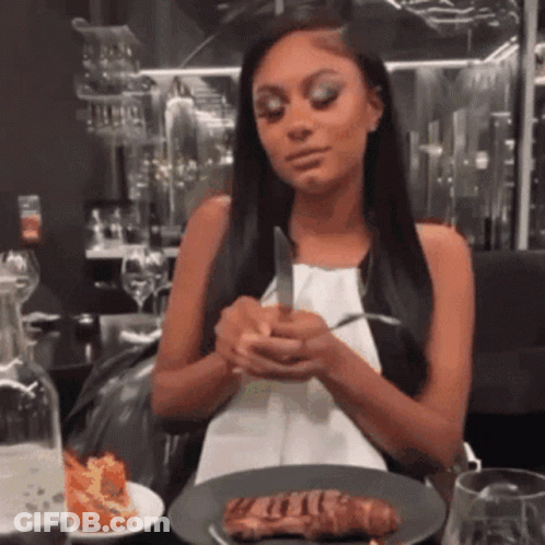 A Woman Is Holding A Knife And Fork In Front Of A Plate Of Meat GIF