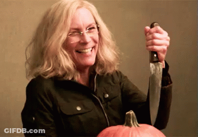 A Woman Is Holding A Knife Over A Pumpkin And Smiling . GIF