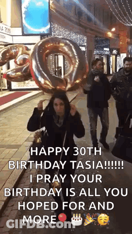 A Woman Is Holding A Large Balloon In The Shape Of A Number 30 . GIF