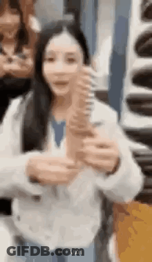 A Woman Is Holding A Large Ice Cream Cone In Her Hand . GIF
