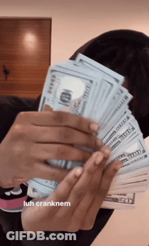 A Woman Is Holding A Large Stack Of Money In Her Hands . GIF