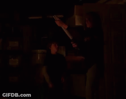 A Woman Is Holding A Light While Standing Next To A Boy In A Blue Shirt GIF