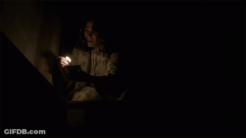 A Woman Is Holding A Lit Candle In Her Hand GIF