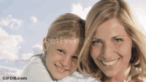 A Woman Is Holding A Little Girl In Her Arms And They Are Both Smiling For The Camera GIF