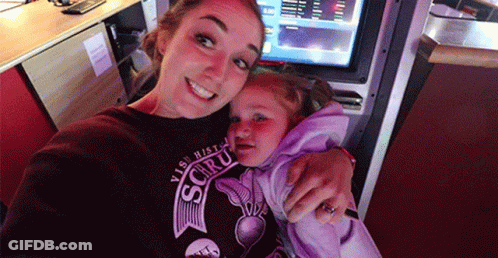 A Woman Is Holding A Little Girl Who Is Wearing A Shirt That Says ' Visit Histo ' On It GIF