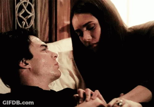 A Woman Is Holding A Man 'S Hand While Laying In Bed . GIF