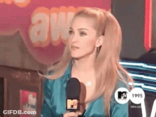 A Woman Is Holding A Microphone In Front Of A Mtv Logo GIF