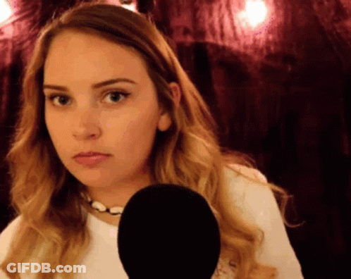 A Woman Is Holding A Microphone In Front Of Her Face And Making A Funny Face GIF