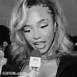A Woman Is Holding A Microphone In Her Hand And Talking Into It . GIF