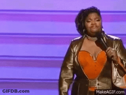A Woman Is Holding A Microphone On A Stage . GIF
