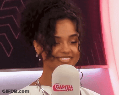 A Woman Is Holding A Microphone That Says Capital Xtra On It GIF