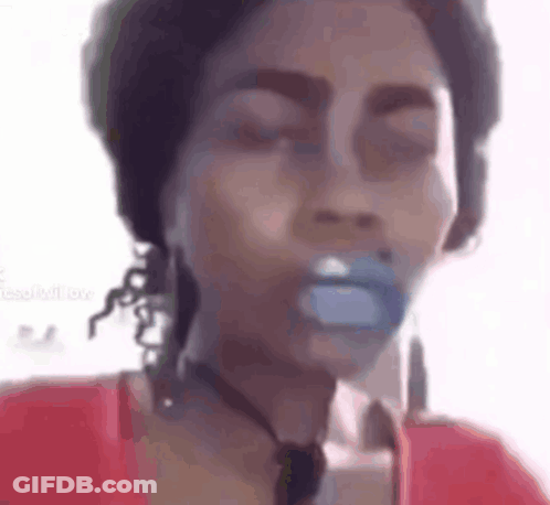 A Woman Is Holding A Pacifier In Her Mouth While Wearing A Red Shirt . GIF