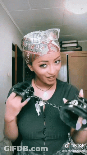A Woman Is Holding A Pair Of Handcuffs In Her Hands . GIF