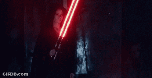A Woman Is Holding A Pair Of Red Lightsabers In Her Hands . GIF