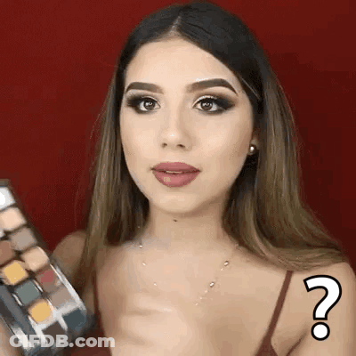 A Woman Is Holding A Palette Of Eye Shadows And Has A Question Mark On Her Arm . GIF