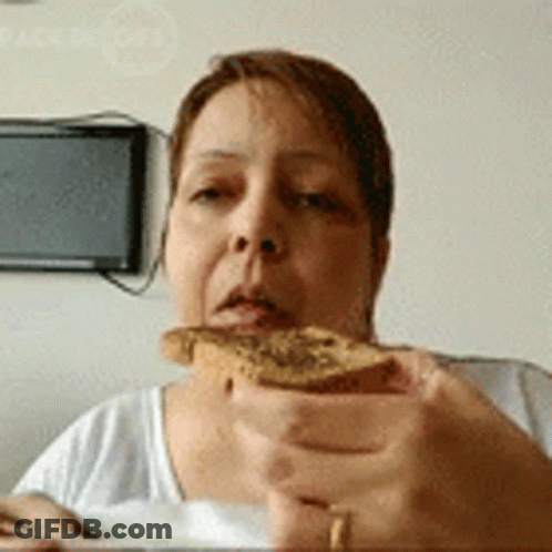 A Woman Is Holding A Piece Of Bread In Front Of Her Face . GIF