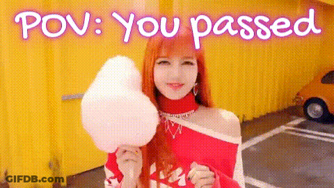 A Woman Is Holding A Piece Of Cotton Candy In Front Of A Yellow Building . GIF