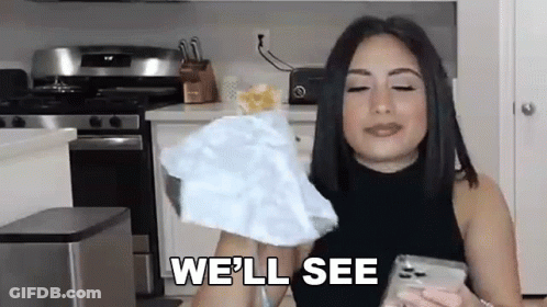 A Woman Is Holding A Piece Of Paper And Saying `` We 'Ll See '' While Standing In A Kitchen . GIF