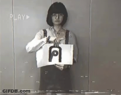 A Woman Is Holding A Piece Of Paper With The Letter A On It GIF