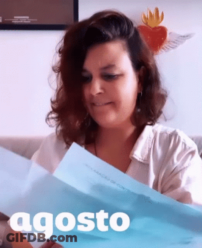 A Woman Is Holding A Piece Of Paper With The Word Agosto On It GIF