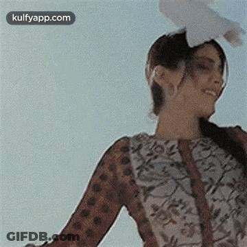 A Woman Is Holding A Pigeon On Her Head . GIF