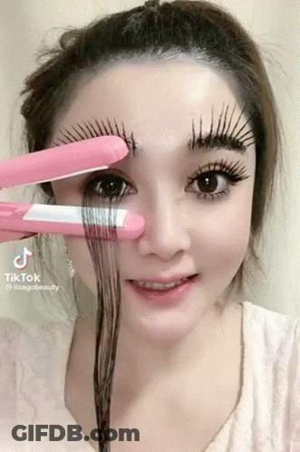 A Woman Is Holding A Pink Hair Straightener Over Her Eyebrows And The Hashtag Tiktok Is On The Bottom Right GIF