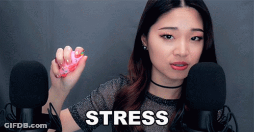 A Woman Is Holding A Pink Object In Front Of Two Microphones And The Word Stress Is On The Screen Behind Her GIF