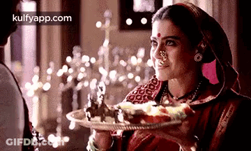 A Woman Is Holding A Plate Of Food In Her Hand And Smiling At A Man . GIF