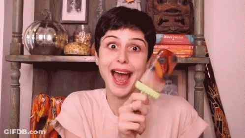 A Woman Is Holding A Popsicle In Her Hand And Making A Face . GIF