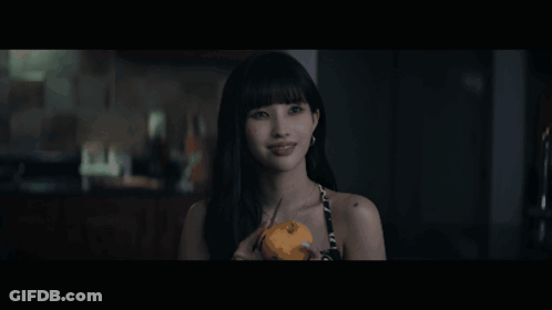 A Woman Is Holding A Pumpkin In Her Hand And Looking At The Camera GIF