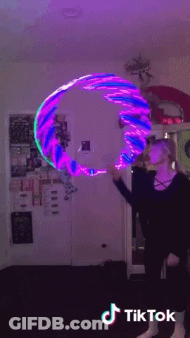 A Woman Is Holding A Purple And Blue Hula Hoop With Tiktok Written On The Bottom Right GIF