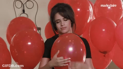 A Woman Is Holding A Red Balloon In Front Of A Bunch Of Red Balloons With Marie Claire Written On The Bottom GIF