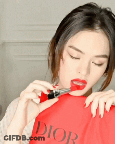 A Woman Is Holding A Red Dior Bag In Her Hand GIF